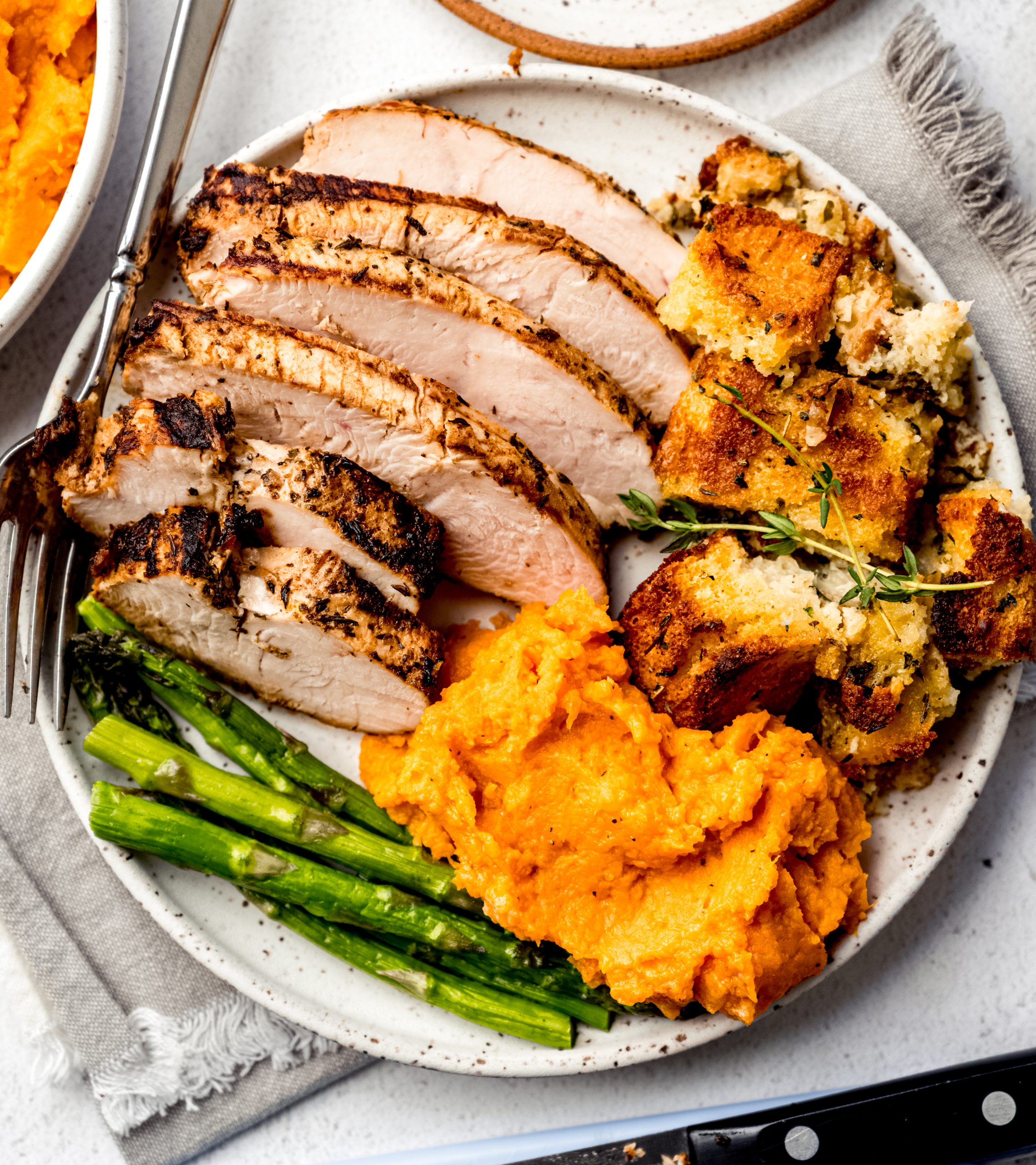 Aerial photo of turkey tenderloin, asparagus, cornbread stuffing, and mashed sweet potatoes.