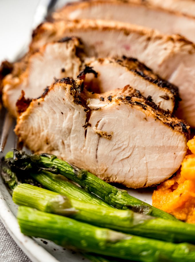 A plate of turkey tenderloin, asparagus, and sweet potatoes.