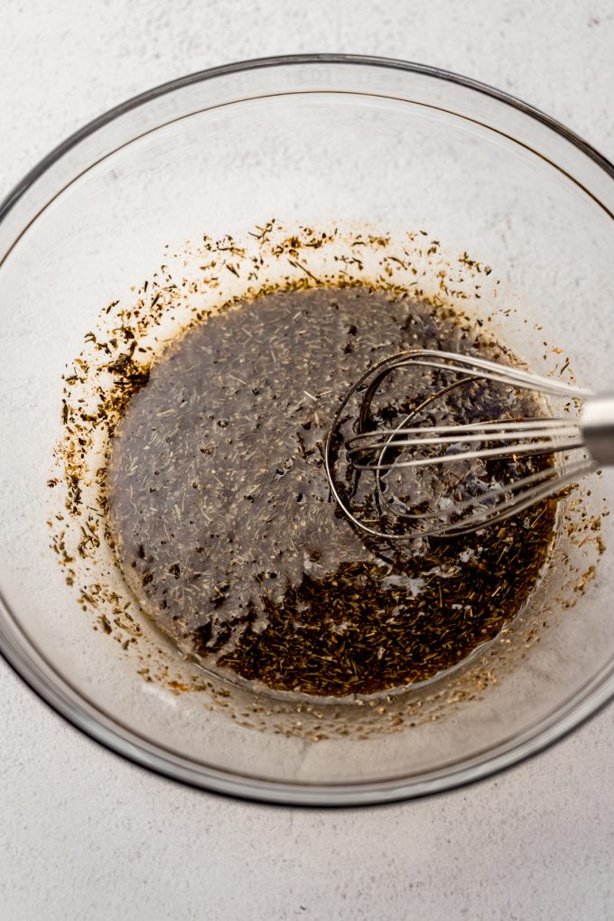 A small bowl with turkey tenderloin marinade in it and someone is whisking it.