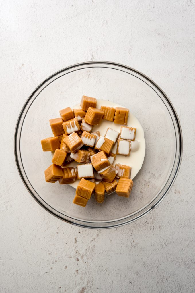 Aerial photo of a bowl of unwrapped caramels and heavy cream.