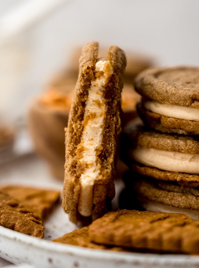 A stack of Biscoff butterscotch sandwich cookies and one on its side that has a bite taken out of it.