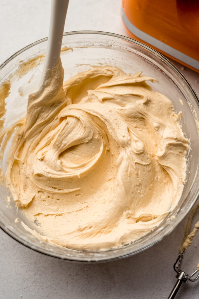 A bowl of butterscotch marshmallow frosting with a spatula in it.