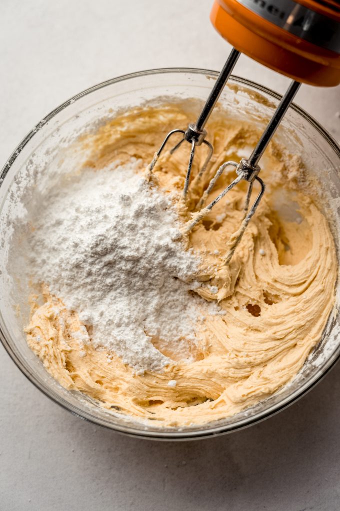 A bowl of butterscotch marshmallow frosting coming together with electric beaters.