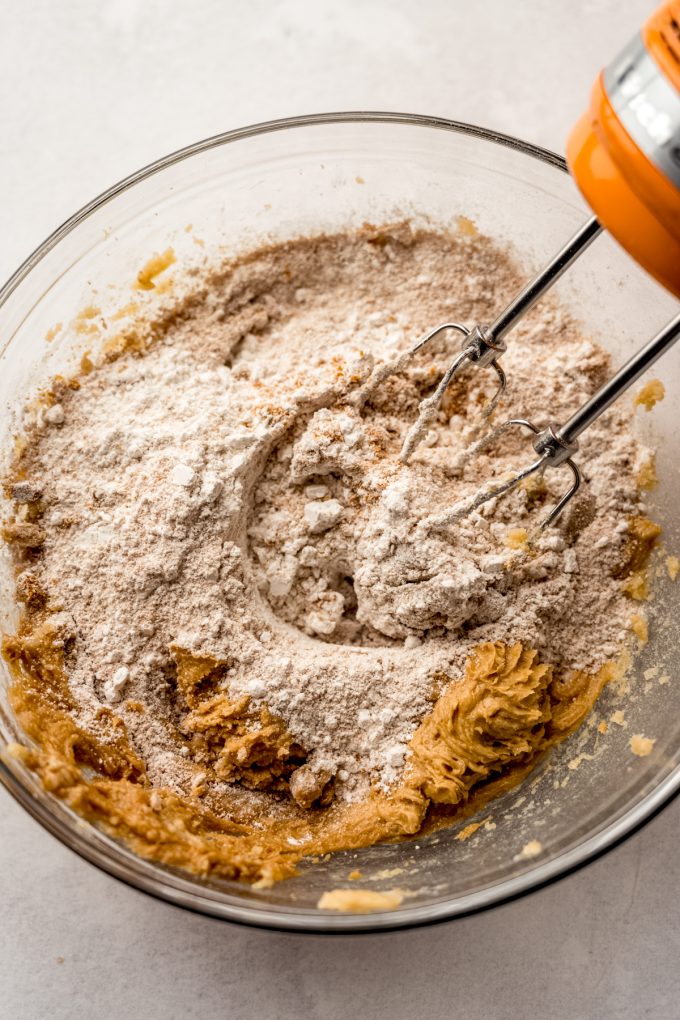 A bowl of Biscoff cookie dough with electric beaters in it.