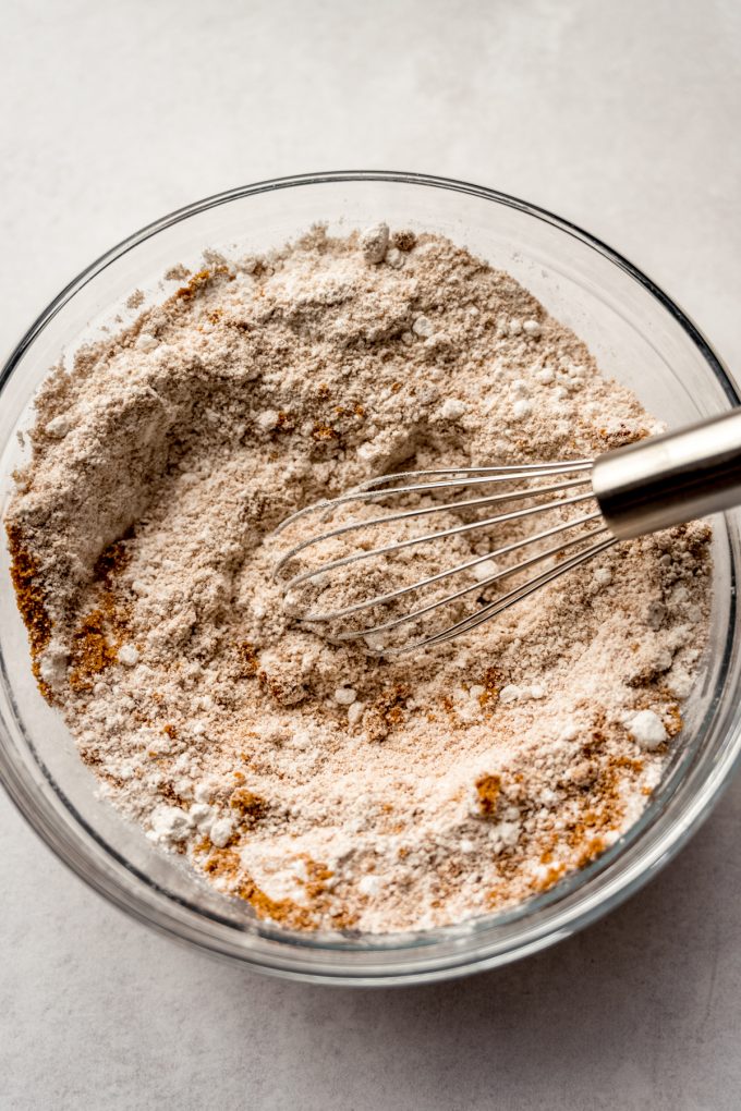 A bowl of flour and Biscoff cookie crumbs with a whisk in it.