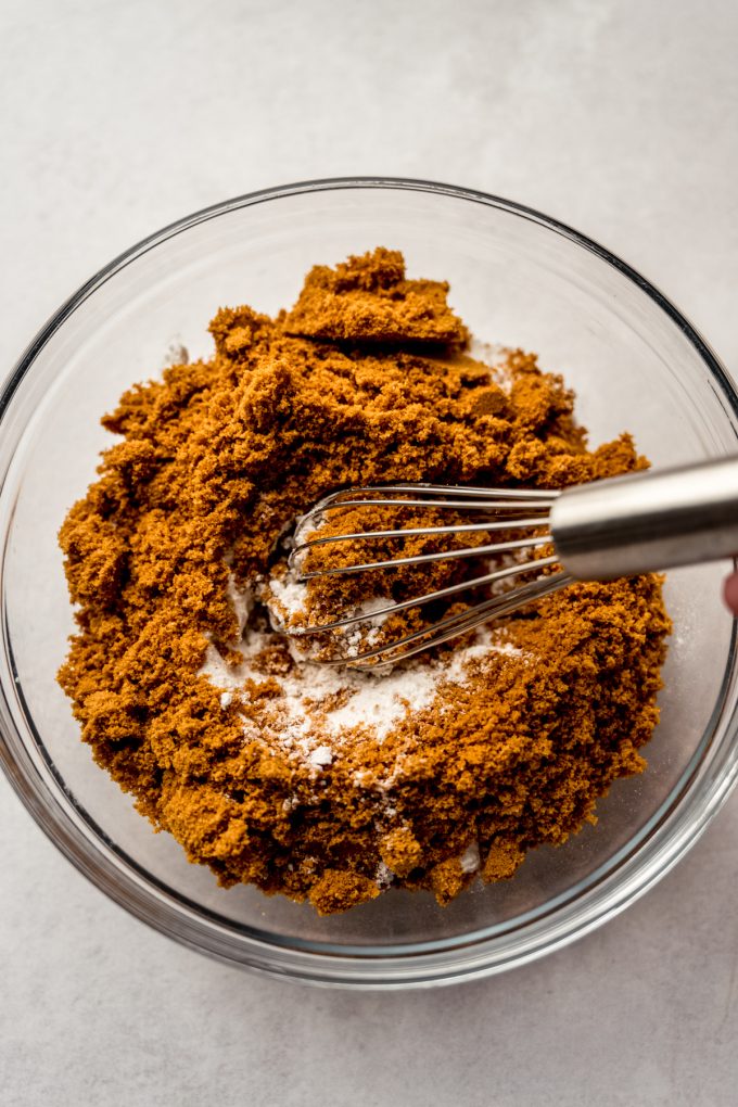 A bowl of flour and Biscoff cookie crumbs with a whisk in it.