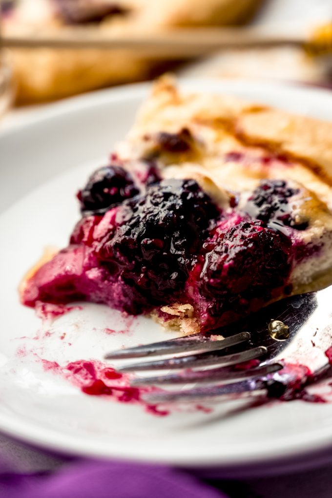 A slice of blackberry galette on a plate with a fork.