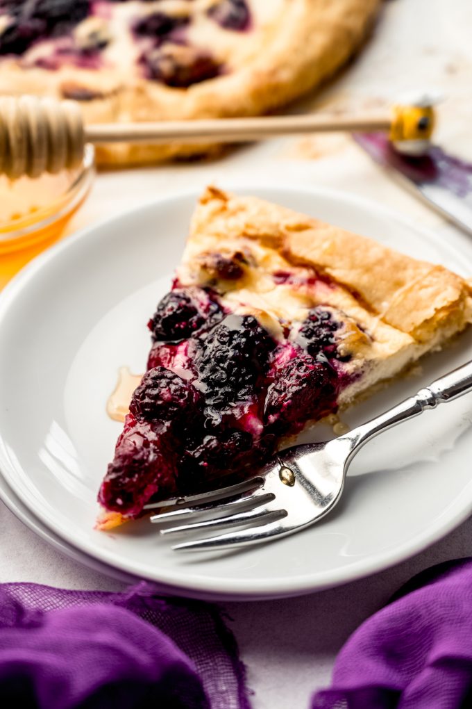 A slice of blackberry galette on a plate with a fork.