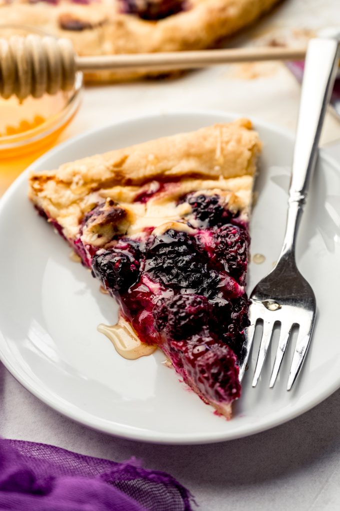 A slice of blackberry galette on a plate with a fork.
