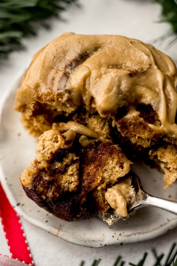 A gingerbread cinnamon roll on a plate with a bite taken out of it.