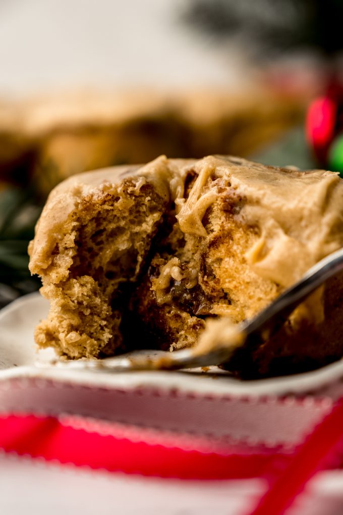 A gingerbread cinnamon roll on a plate with a bite taken out of it.