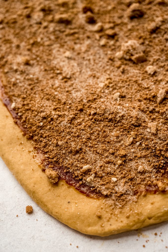 A rectangle of gingerbread cinnamon roll dough with filling on it.