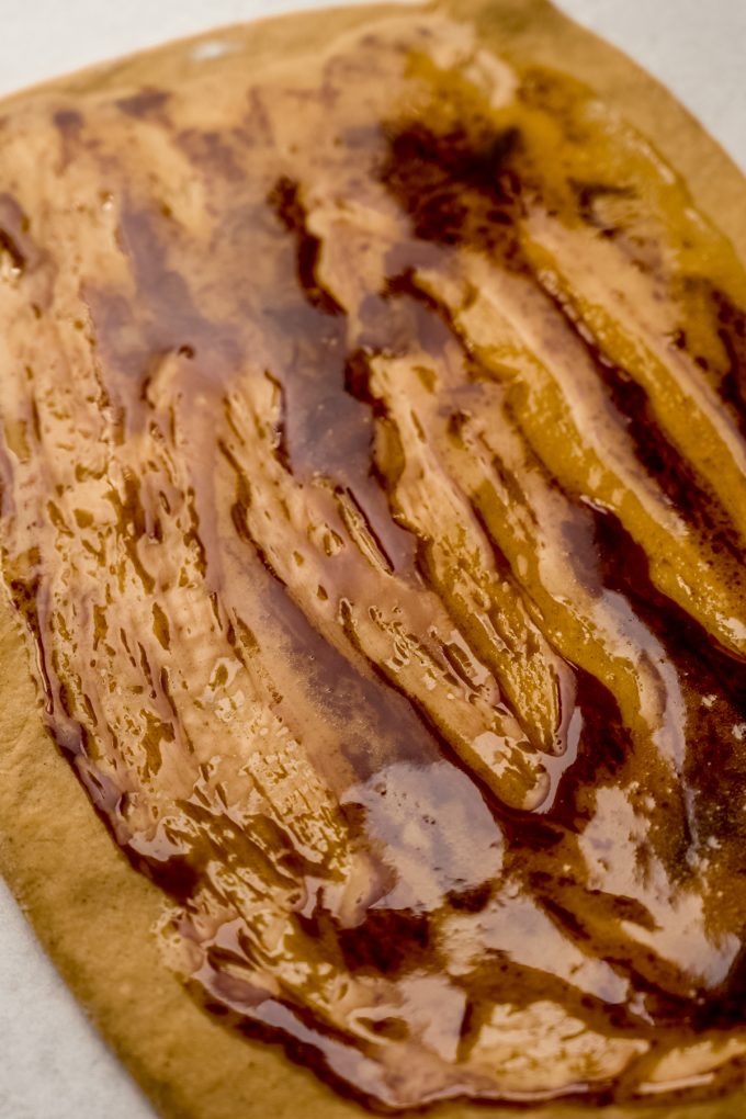 A rectangle of gingerbread cinnamon roll with butter and molasses spread onto it.