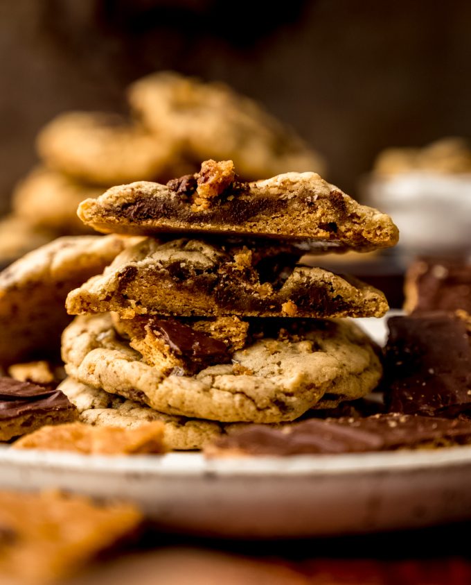 A stack of graham cracker toffee cookies and the one on top has been cut in half so you can see the cross section of the cookie.