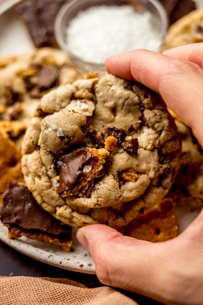 Someone is holding a graham cracker toffee cookie over a plate of others.