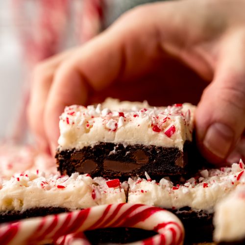 Someone is grabbing a peppermint bark cookie bar from a stack of other bars.