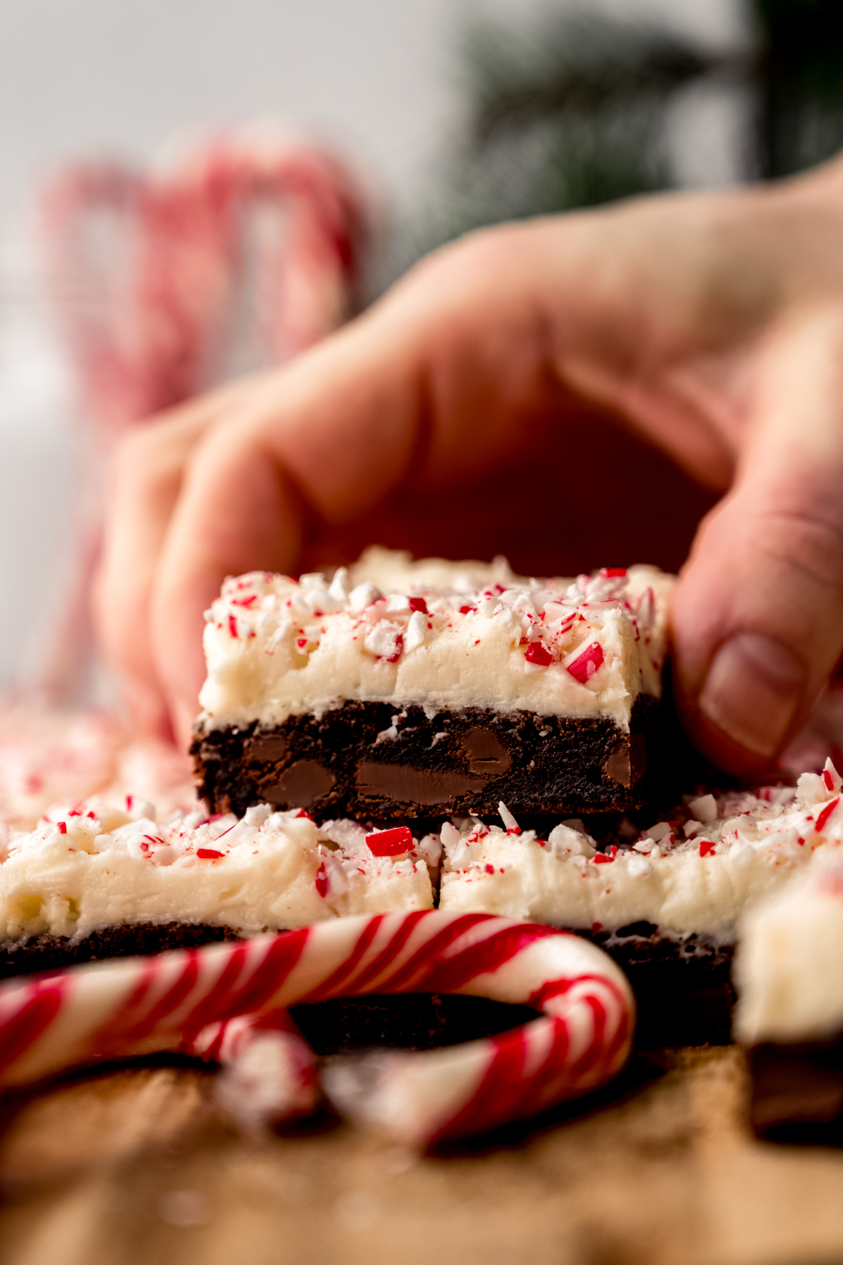 Someone is grabbing a peppermint bark cookie bar from a stack of other bars.