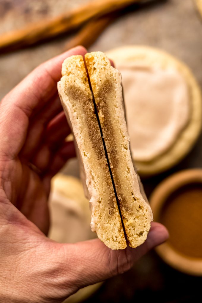 A photo of someone holding a brown sugar Pop Tart cookie that has been cut in half so you can see the inside.