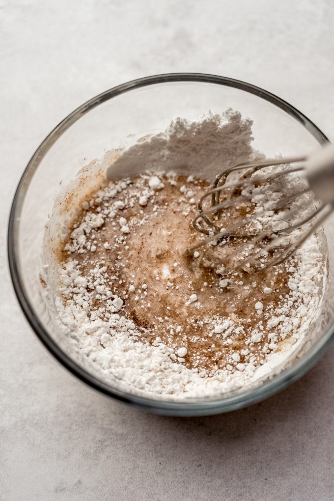 A bowl full of the ingredients for cinnamon sugar glaze being whisked.