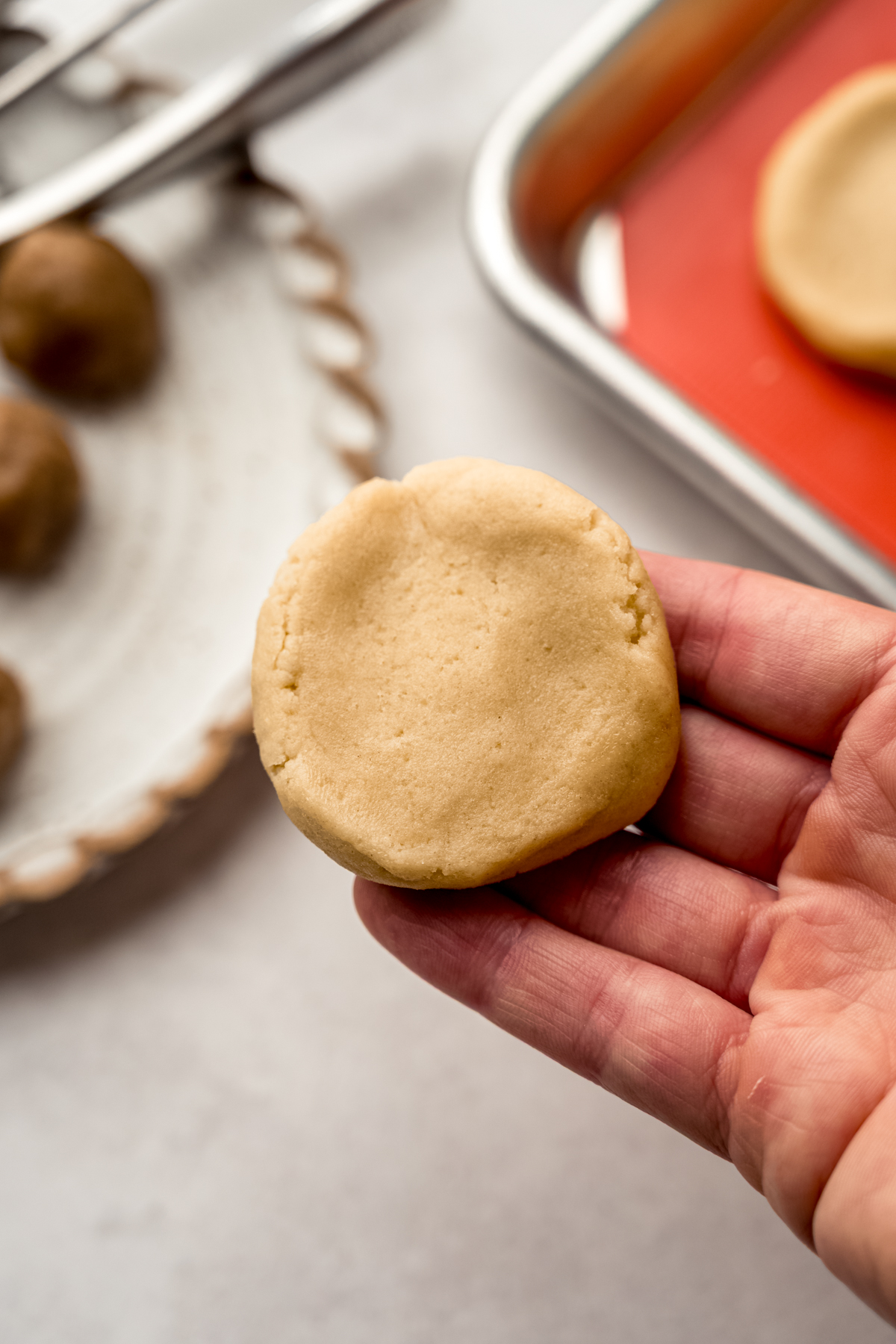 Someone is holding a disc of cookie dough ready to make a stuffed cookie.