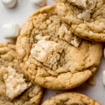 Rice Krispie cookies on a surface with mini marshmallows and cereal around it.
