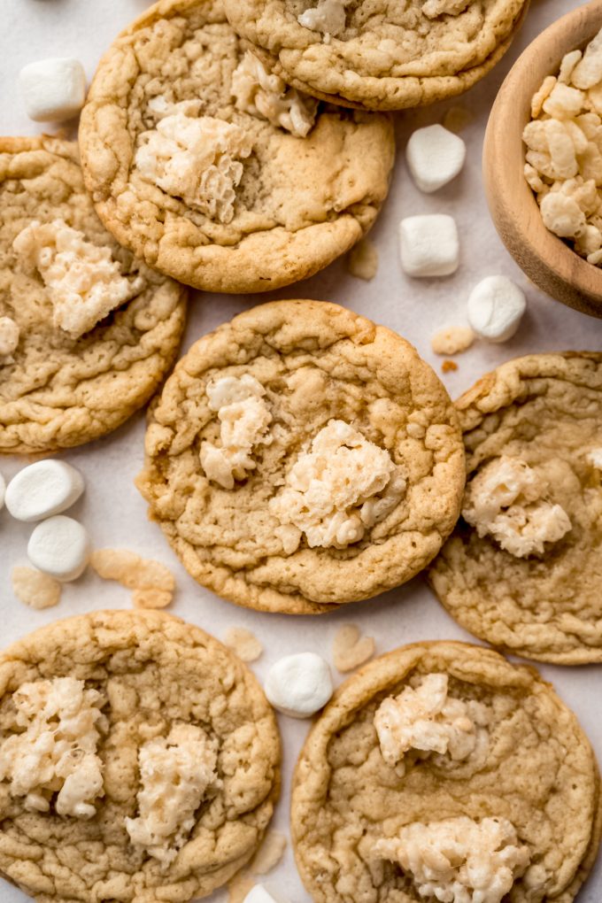 Rice Krispie cookies on a surface with mini marshmallows and cereal around it.