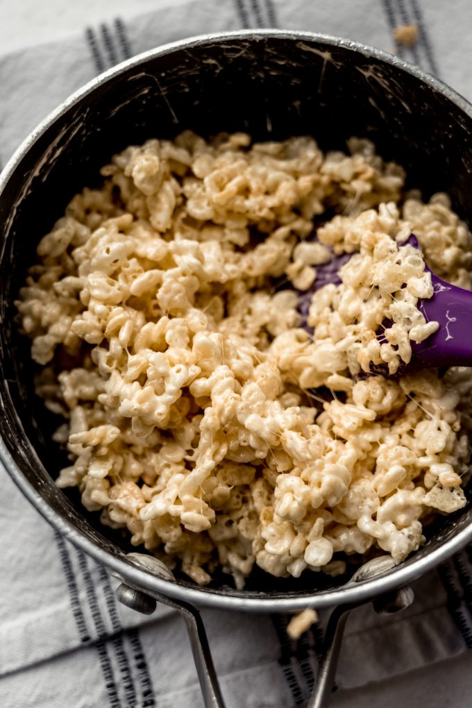 A saucepan of Rice Krispie treat mix with a spatula in it.