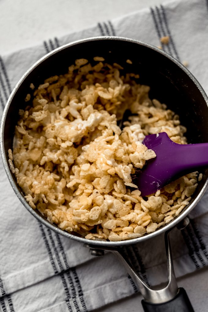 A saucepan of Rice Krispie treat mix with a spatula in it.