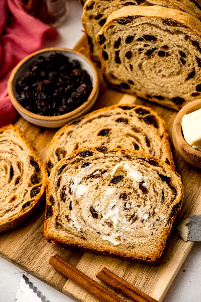 Buttered, sliced cinnamon raisin bread on a surface.