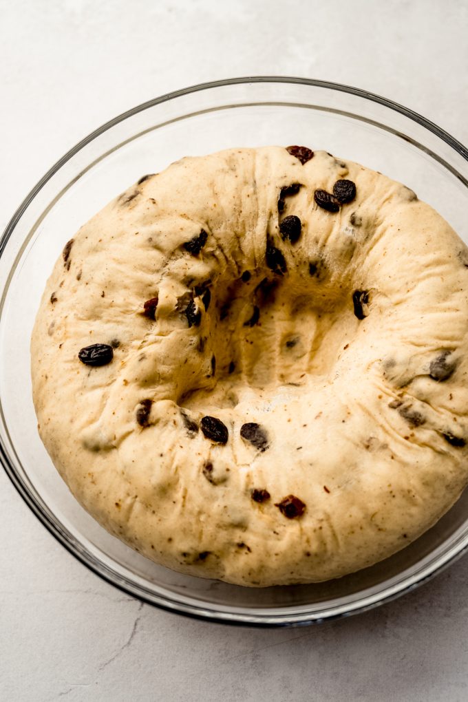 Cinnamon raisin bread dough that has been punched down in a glass bowl.