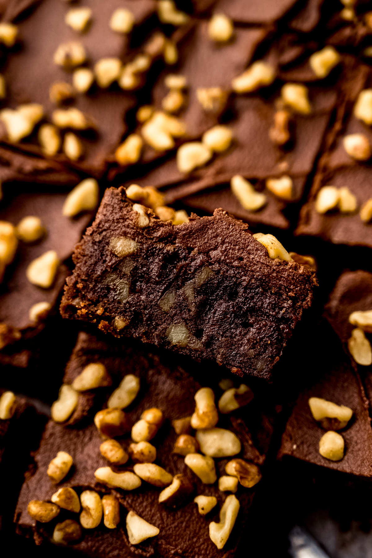 Frosted brownies with walnuts sliced and on a surface.