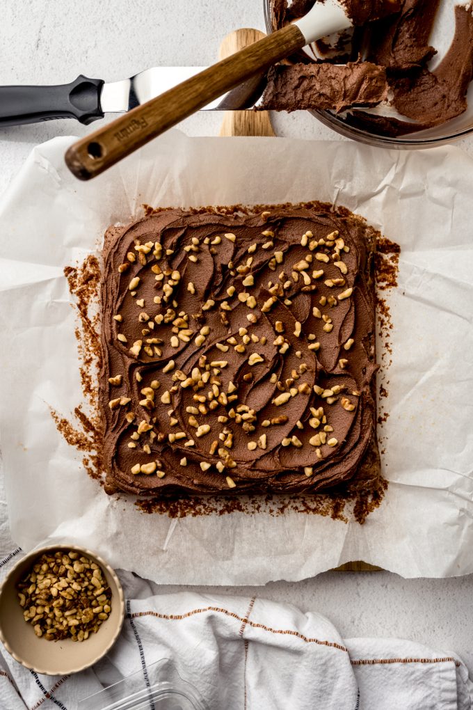 Aerial photo of frosted brownies with walnuts on a surface before getting sliced.