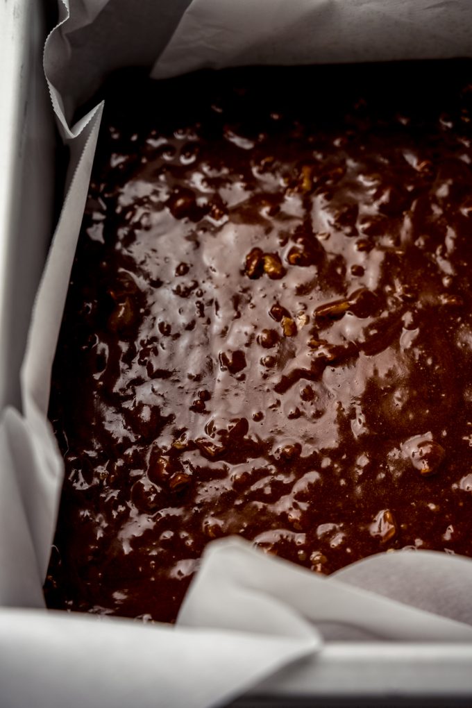 Brownie batter with walnuts in it in a baking pan.