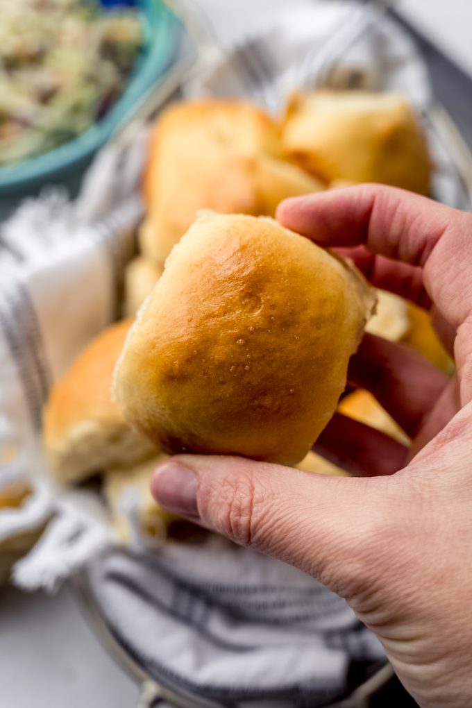 Someone is holding a slider bun in their hand so you can see the top of the roll.