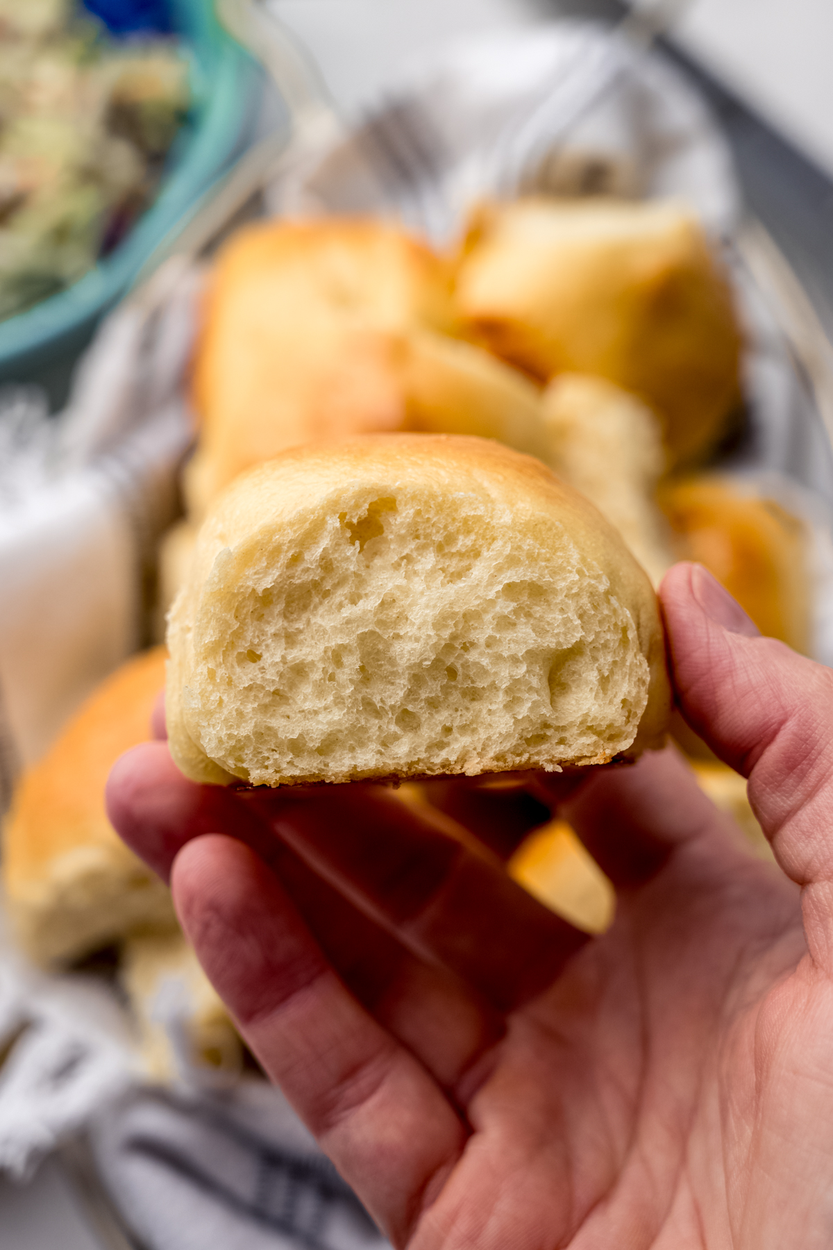 Someone is holding a slider bun in their hand so you can see the side of the roll.
