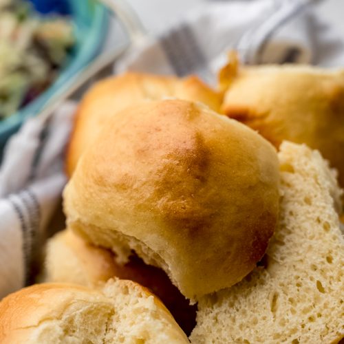 Mini slider buns that have been sliced and are sitting in a bread basket.