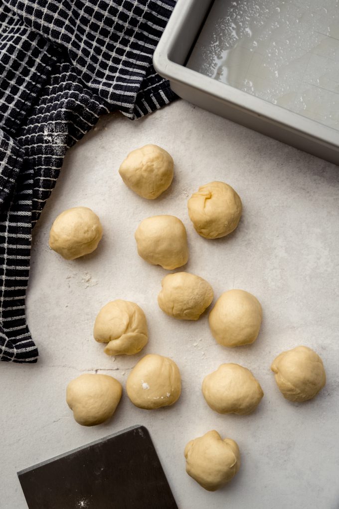 Slider roll dough portioned into balls on a surface.