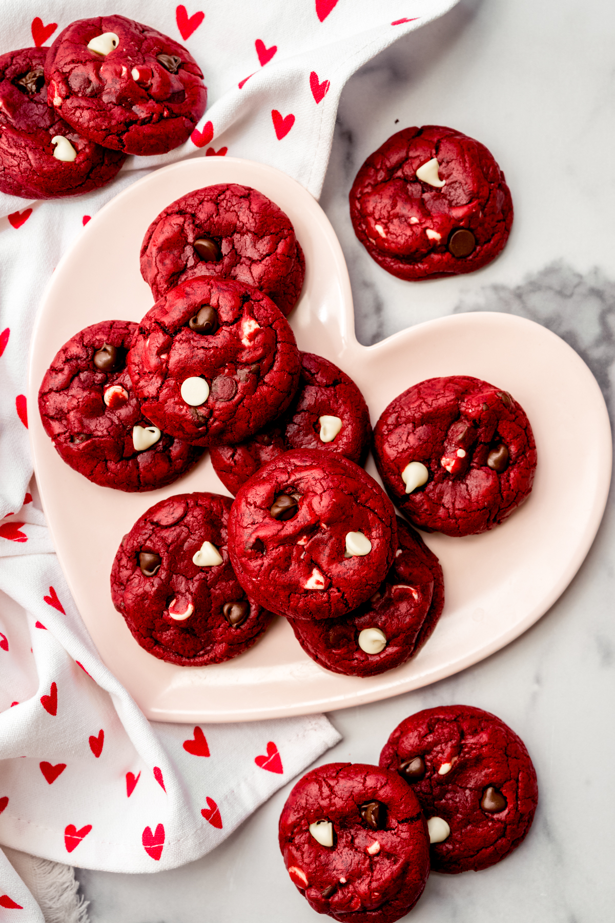 Aerial photo of red velvet chocolate chip cookies on a heart shaped plate.