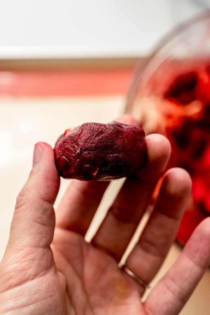 A hand holding a disc of red velvet chocolate chip cookie dough.