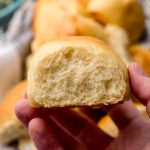 Someone is holding a slider bun in their hand so you can see the side of the roll.