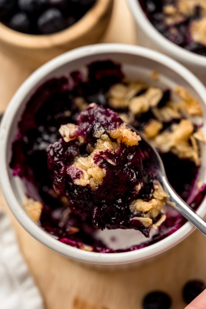 A spoonful of blueberry crisp scooped out of a ramekin.