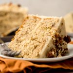 A slice of butter pecan cake on a plate with a fork.