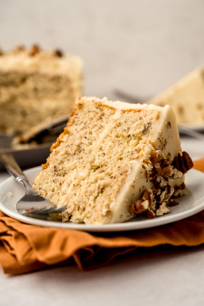 A slice of butter pecan cake on a plate with a fork.
