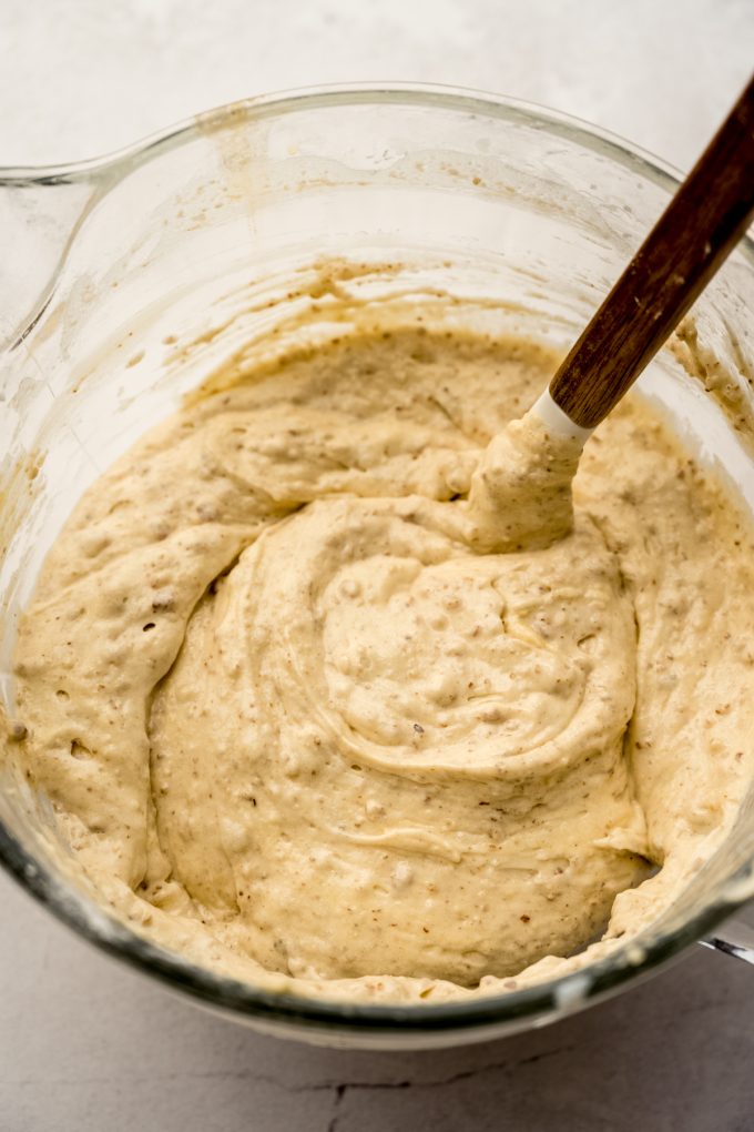 The batter for butter pecan cake in the bowl of a stand mixer with a spatula in it.