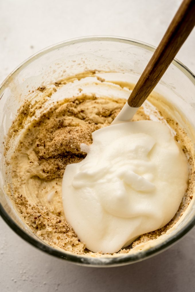 The batter for butter pecan cake in the bowl of a stand mixer with a spatula in it.