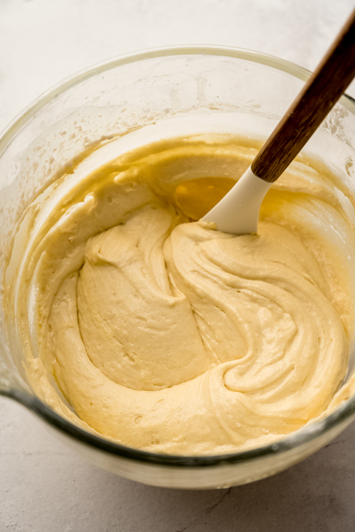 The batter for butter pecan cake in the bowl of a stand mixer with a spatula in it.