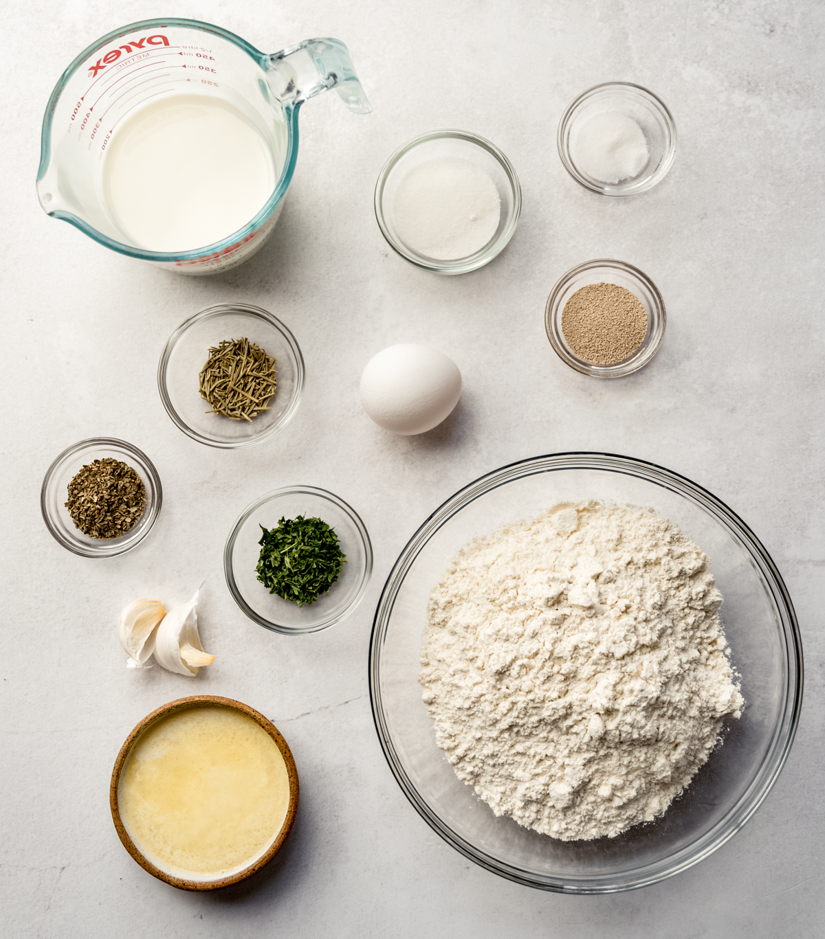 Aerial photo of ingredients to make herbed skillet rolls on a surface.