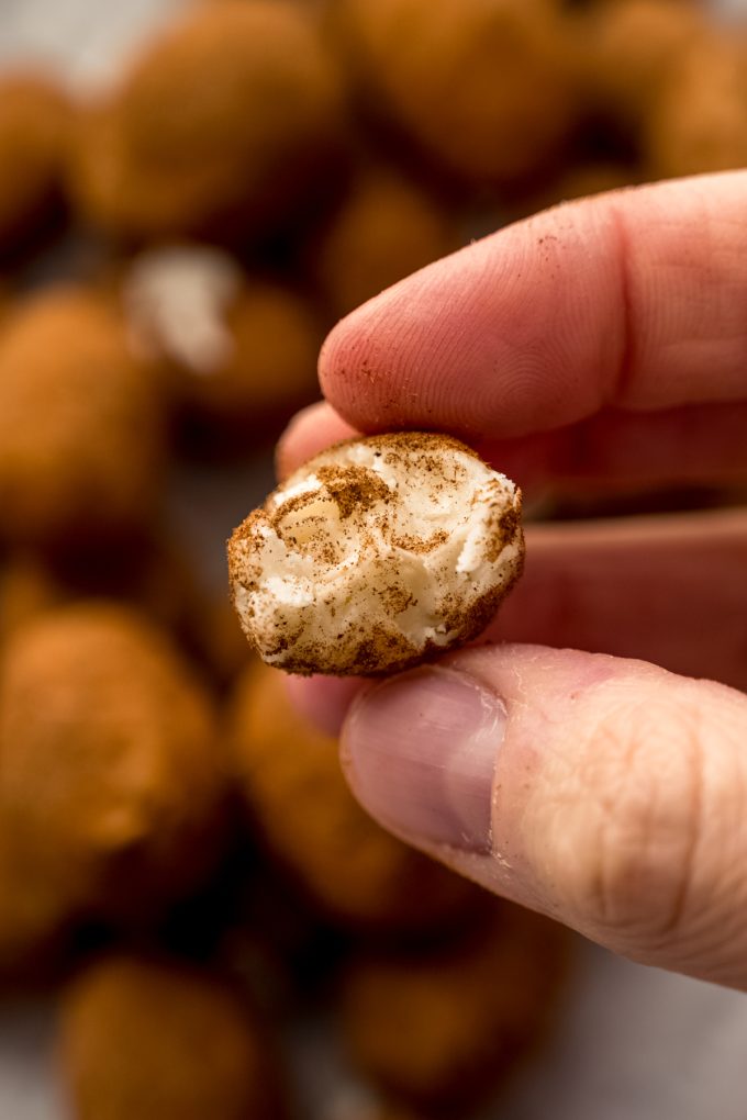 Someone is holding an Irish potato that has a bite taken out of it.