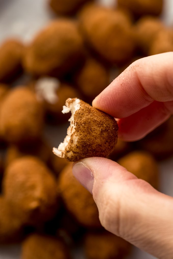 Someone is holding an Irish potato that has a bite taken out of it.