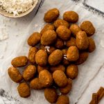Aerial photo of Irish potato candy on a surface with a bowl of shredded coconut and cinnamon sticks around it.